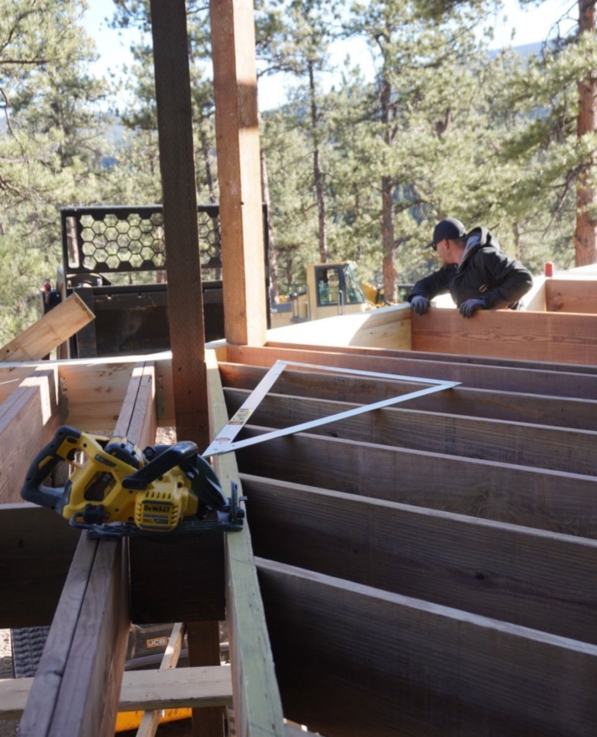Back of a two-story gray house with deck and stairs leading down to a grassy yard on a sunny day.