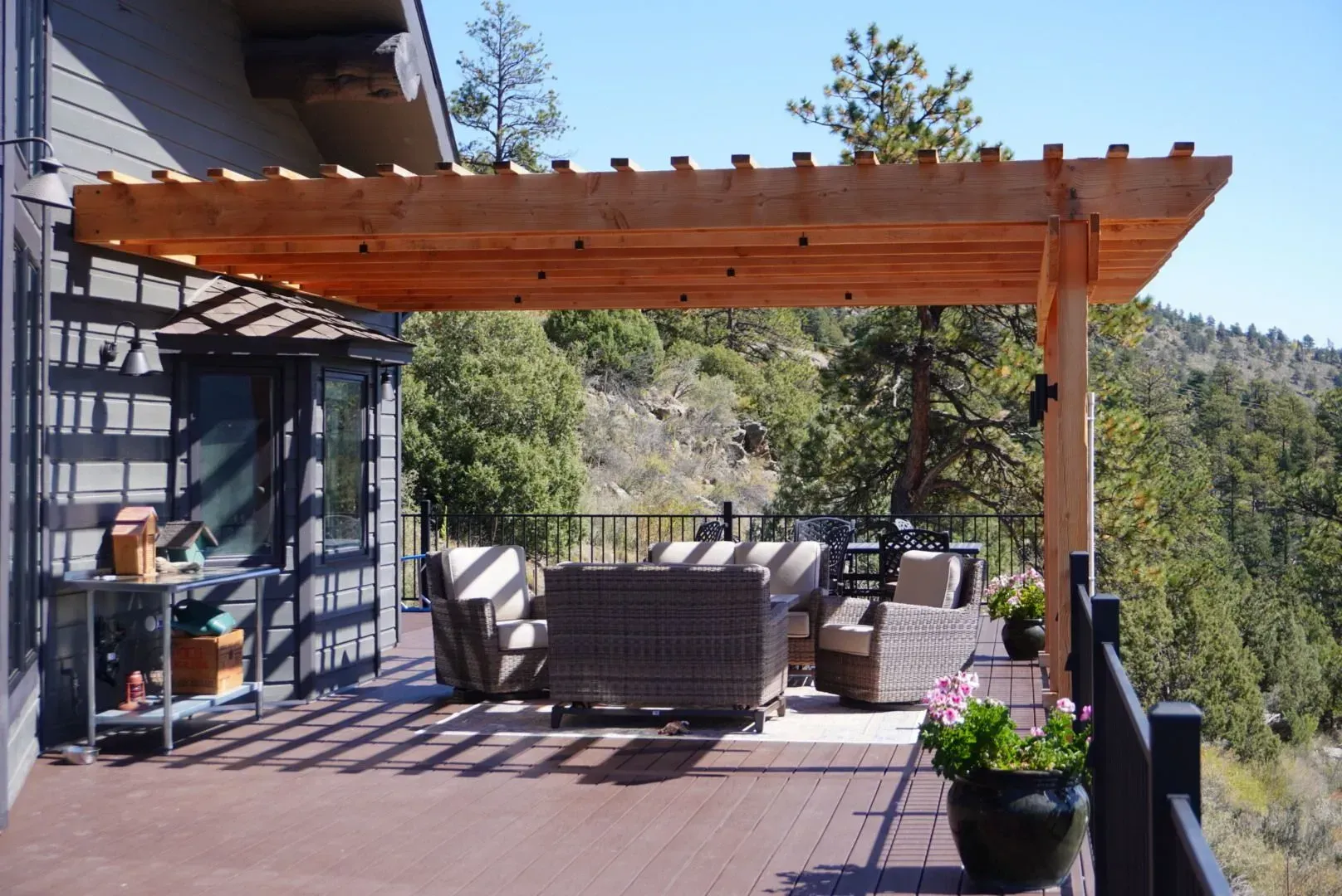 Wooden pergola over deck with seating overlooking a mountain view.
