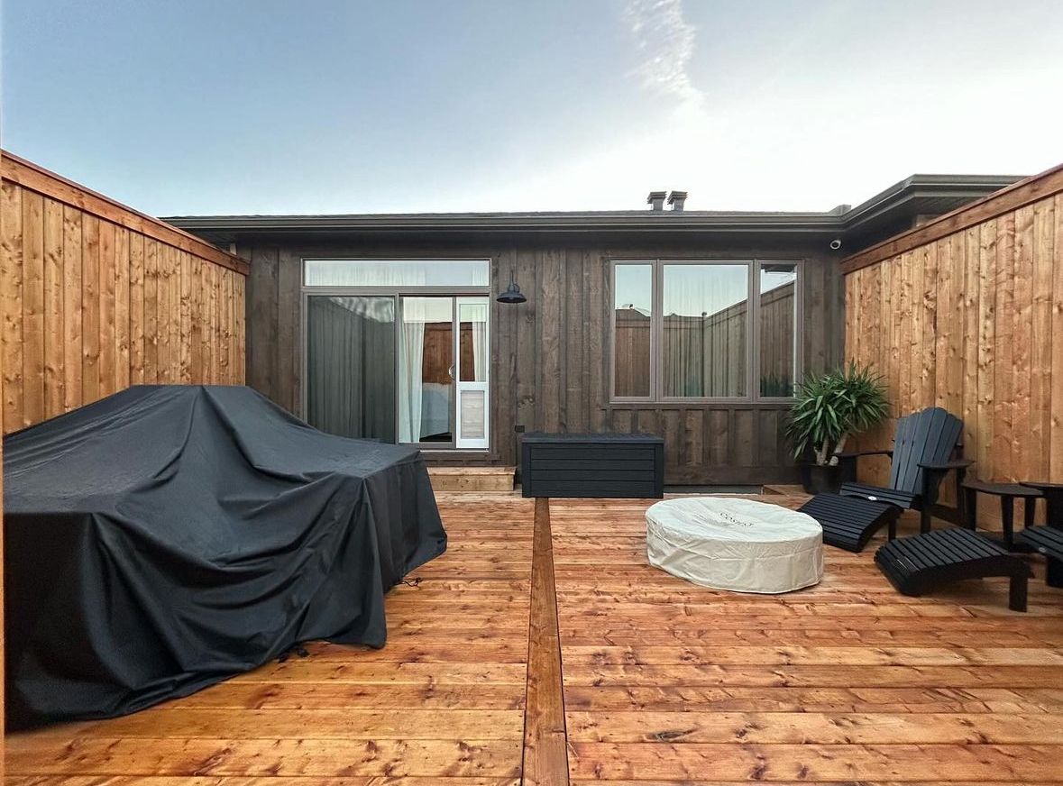 A wooden deck with a couch and chairs and a fire pit.