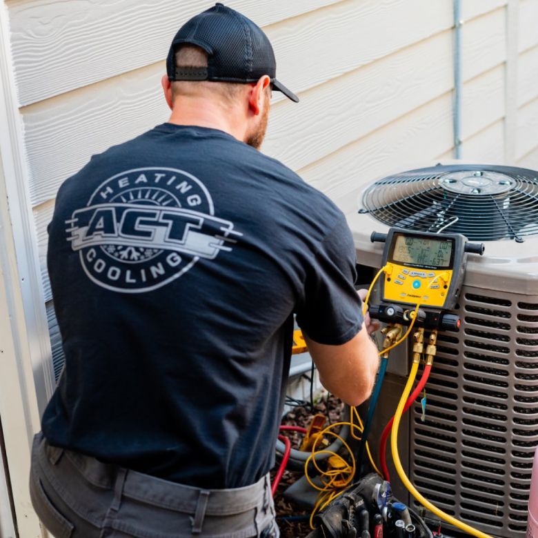 HVAC technician in black shirt, working on an air conditioning unit outside a building.