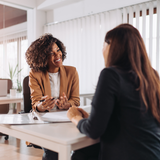 Two women are sitting at a table having a conversation.