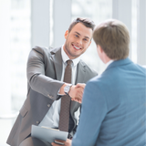 A man in a suit and tie shakes hands with another man