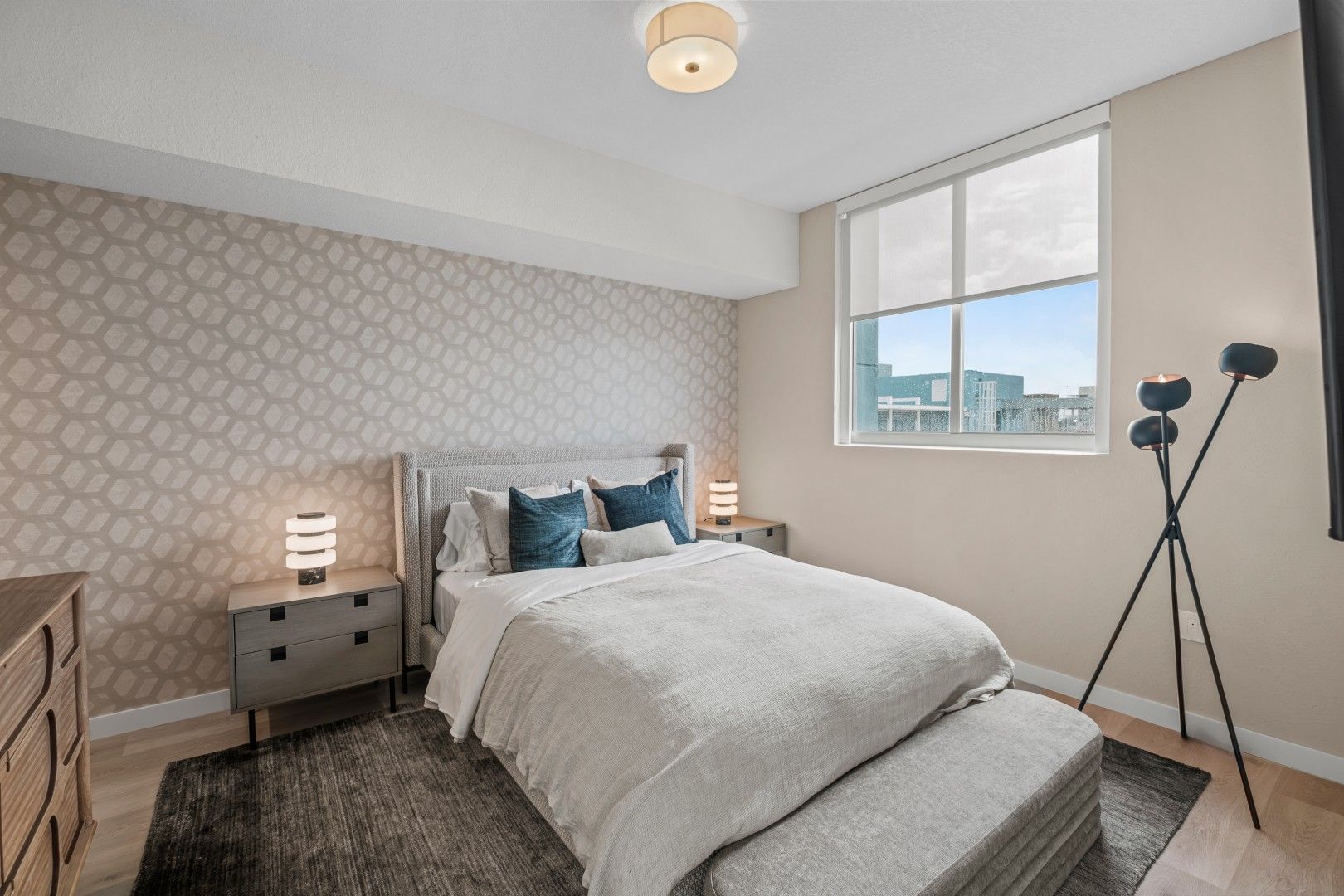 A bedroom with a bed , dresser , nightstand and television.
