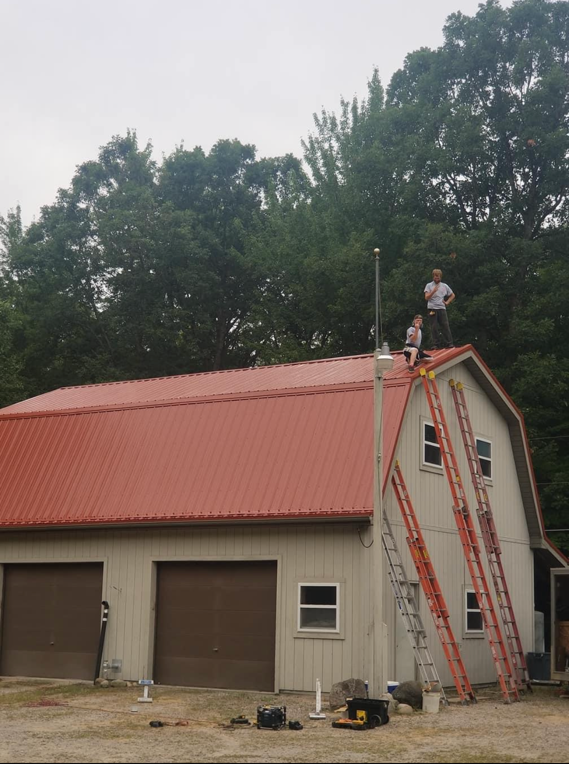 Two men are standing on the roof of a barn