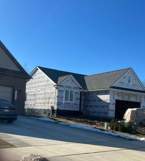 A car is parked in front of a house under construction.