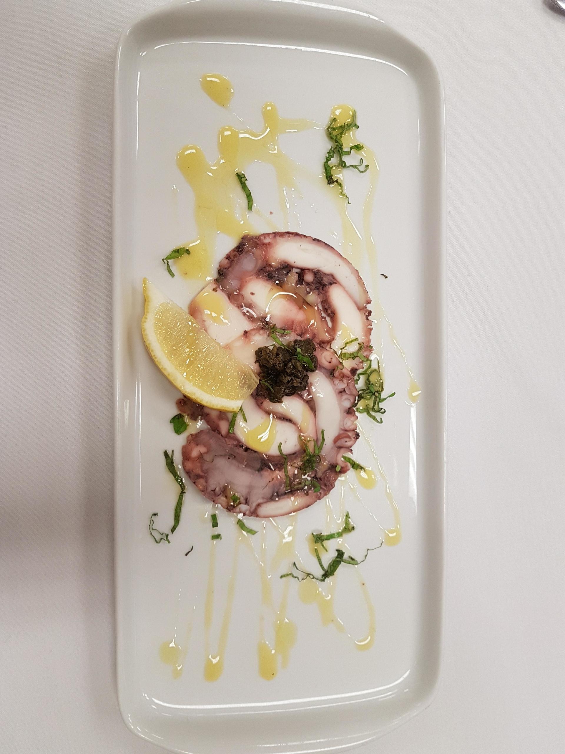 a white plate topped with octopus and lemon slices