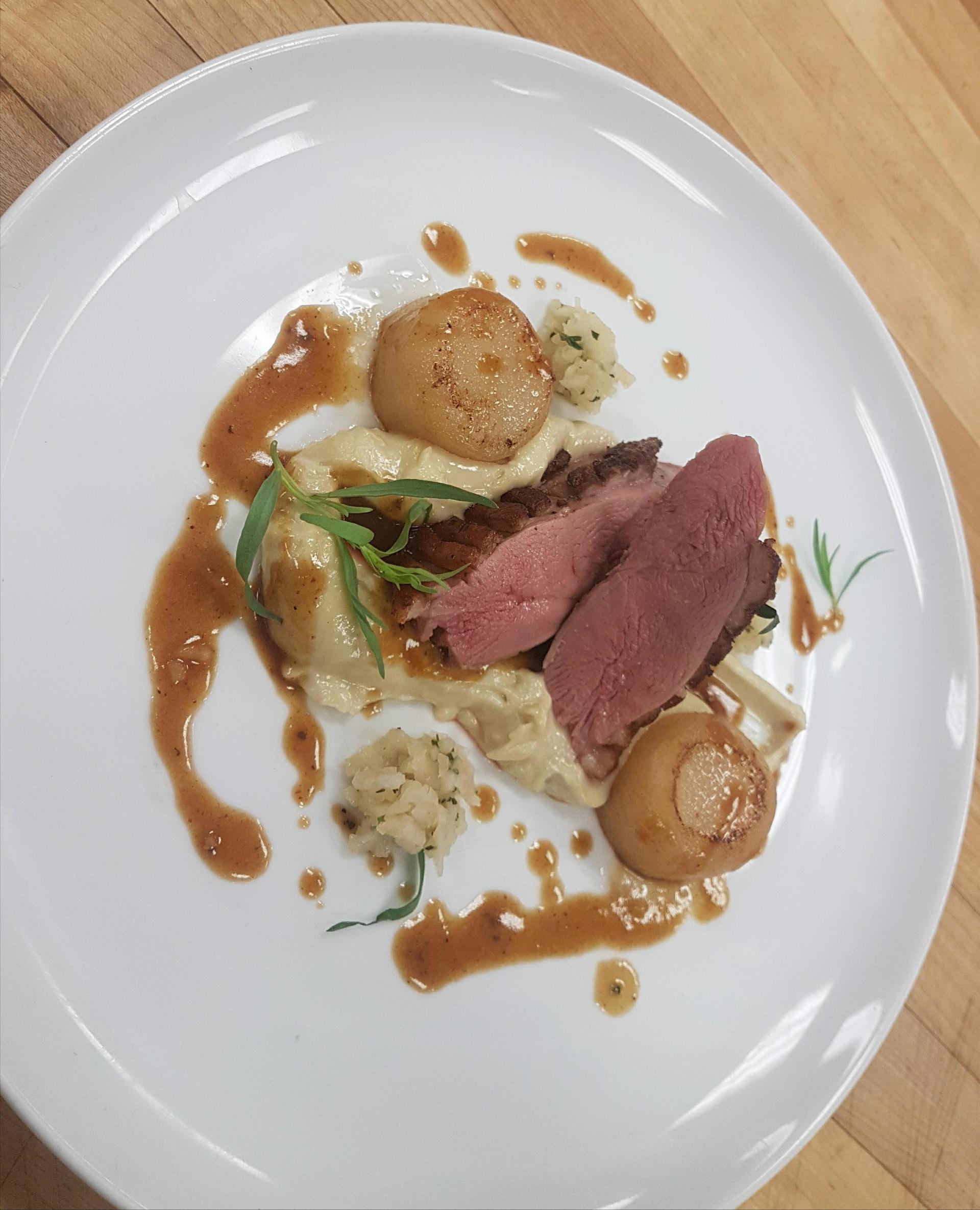 a white plate topped with meat and sauce on a wooden table