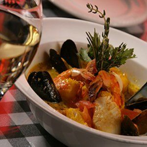 a bowl of food with a glass of wine in the background