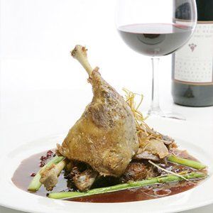 a plate of food next to a glass of wine and a bottle of wine