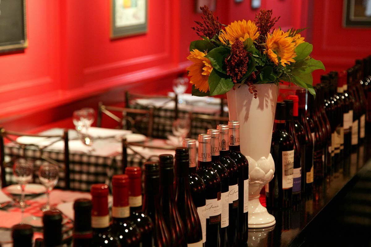 a row of wine bottles are lined up on a table in a restaurant .