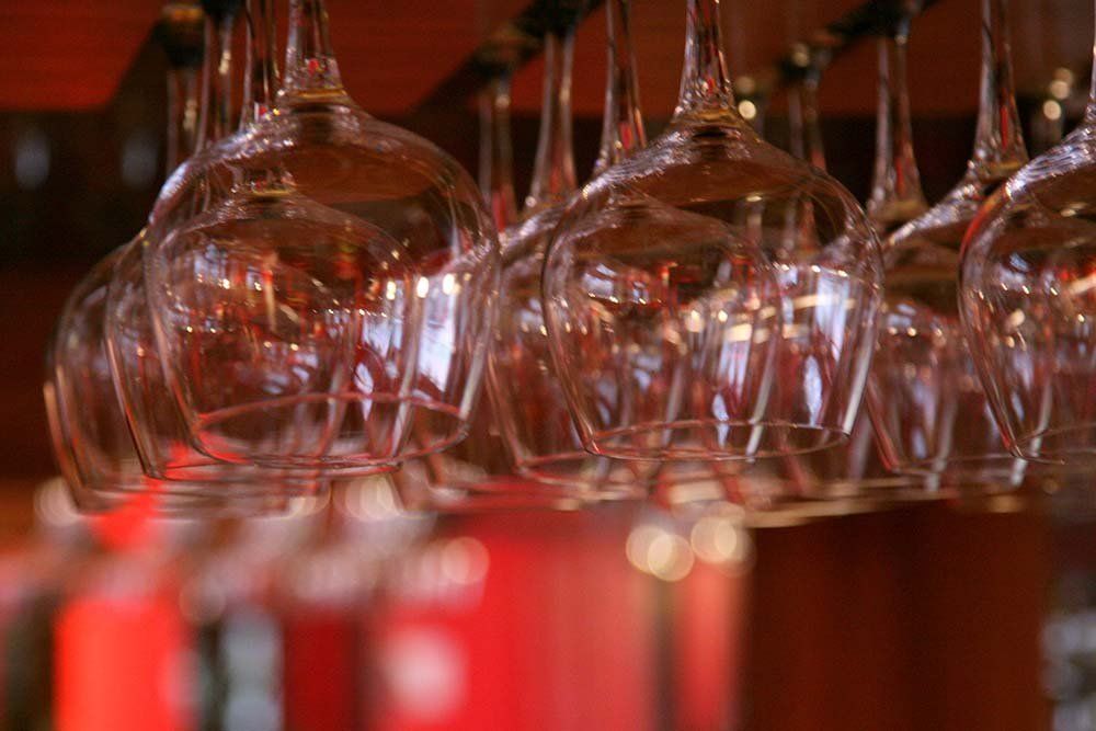a row of wine glasses hanging from a rack in a bar .