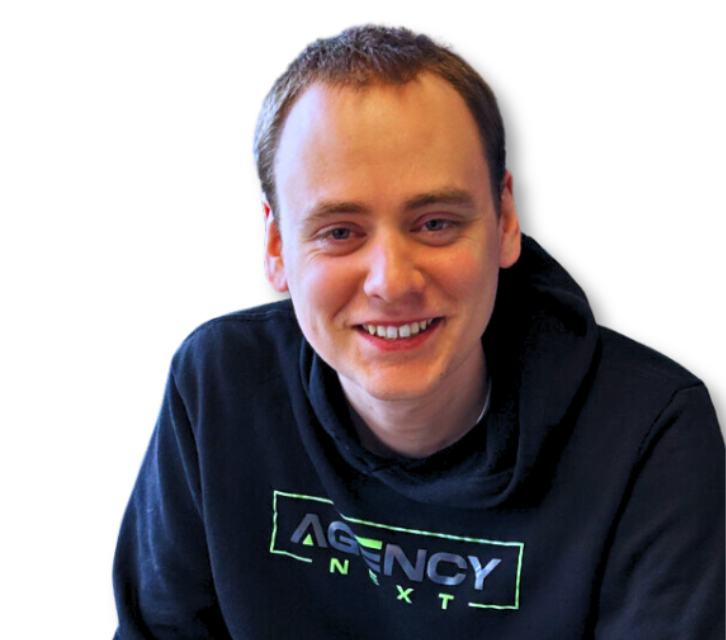 A young man wearing a black agency next sweatshirt smiles for the camera