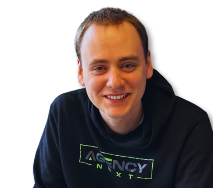 A young man wearing a black agency next sweatshirt smiles for the camera