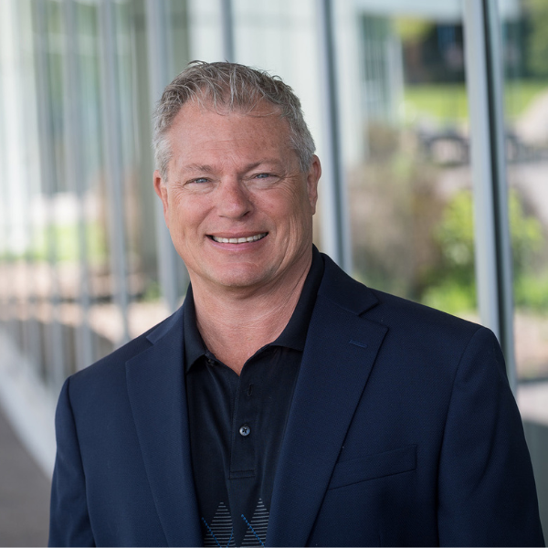 A man in a suit and black shirt is smiling for the camera.