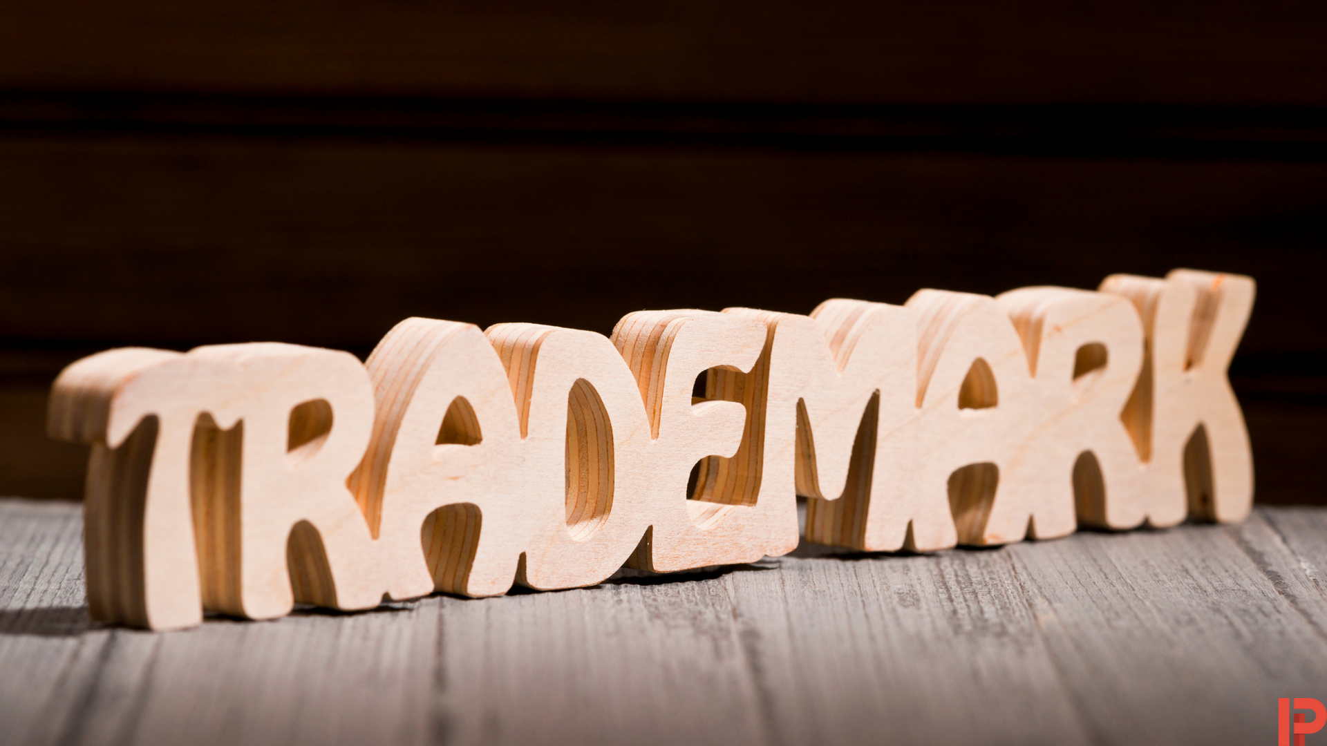 The word trademark is made of wood and is sitting on a wooden table.