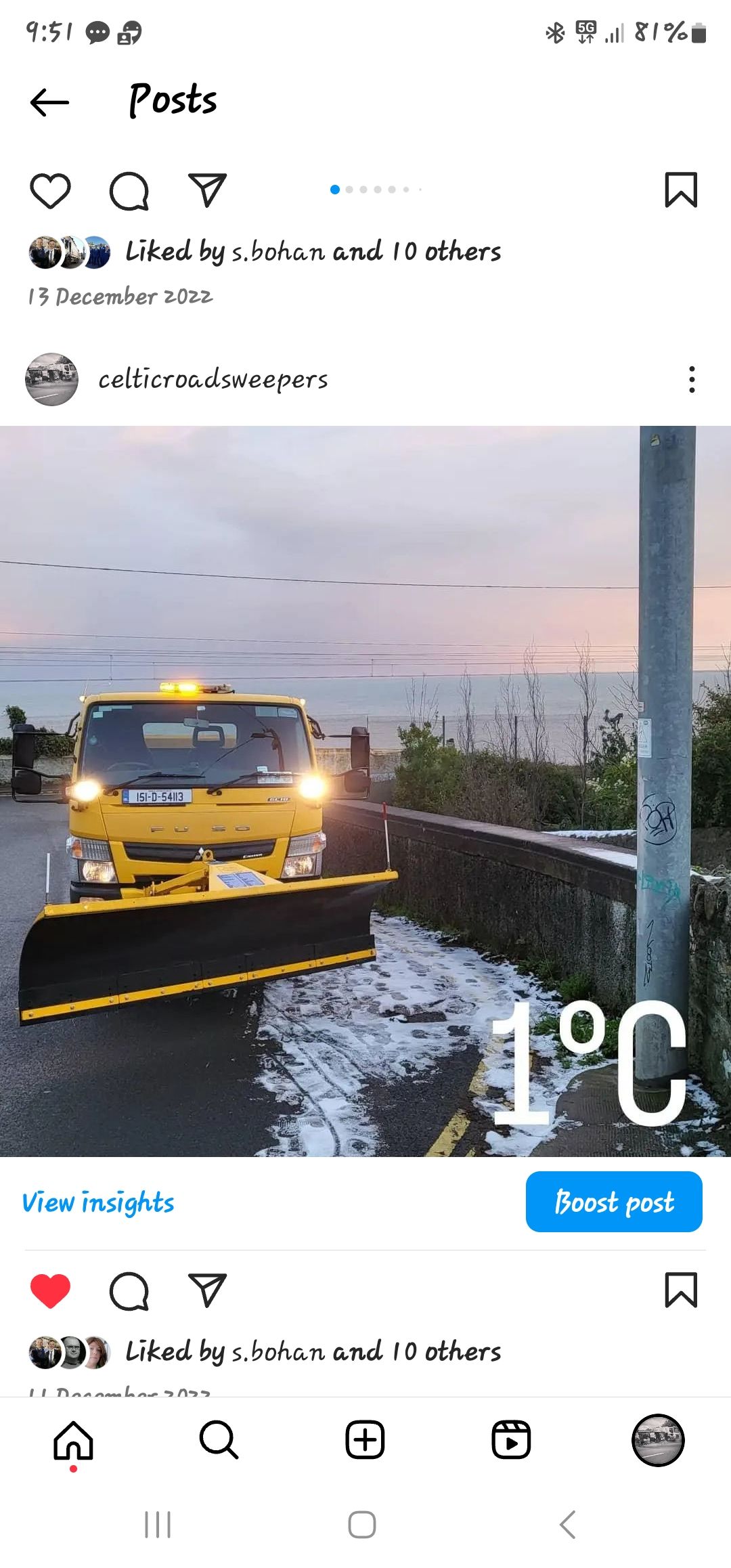 A yellow truck is plowing snow on the side of a road.
