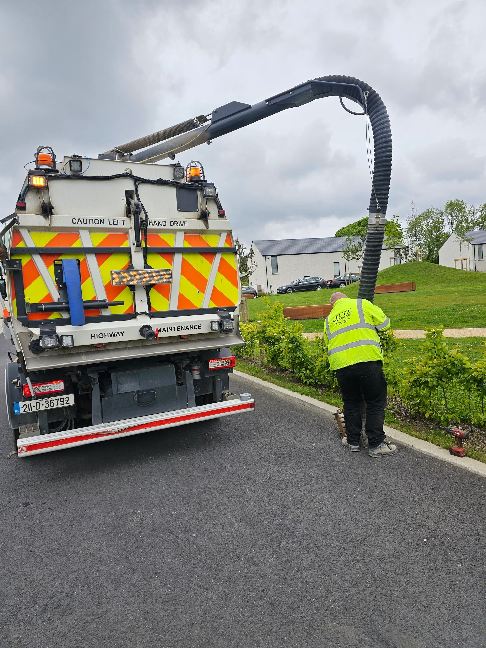 A man in a yellow vest is standing next to a vacuum truck.