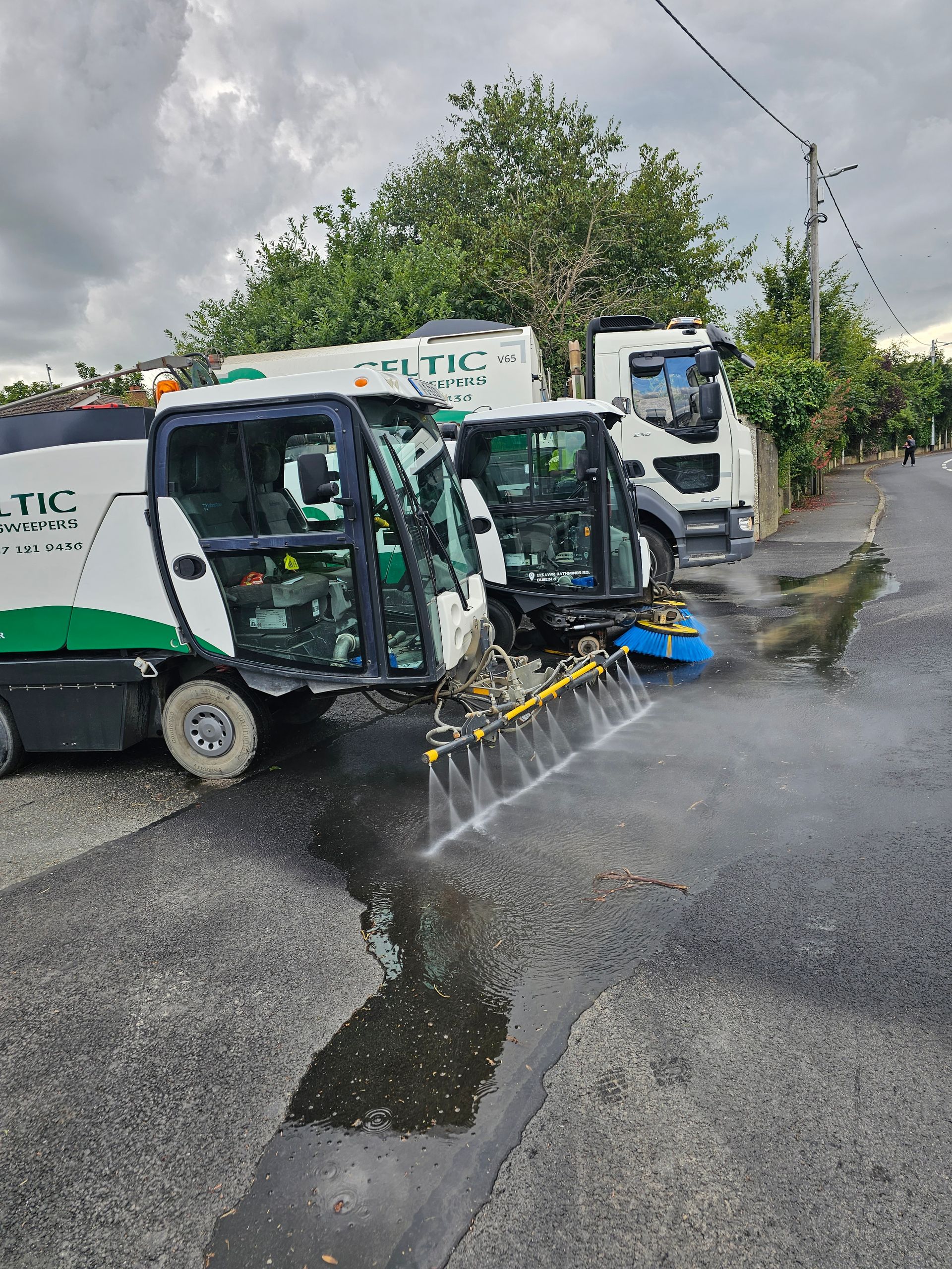 A row of vehicles are spraying water on a street.