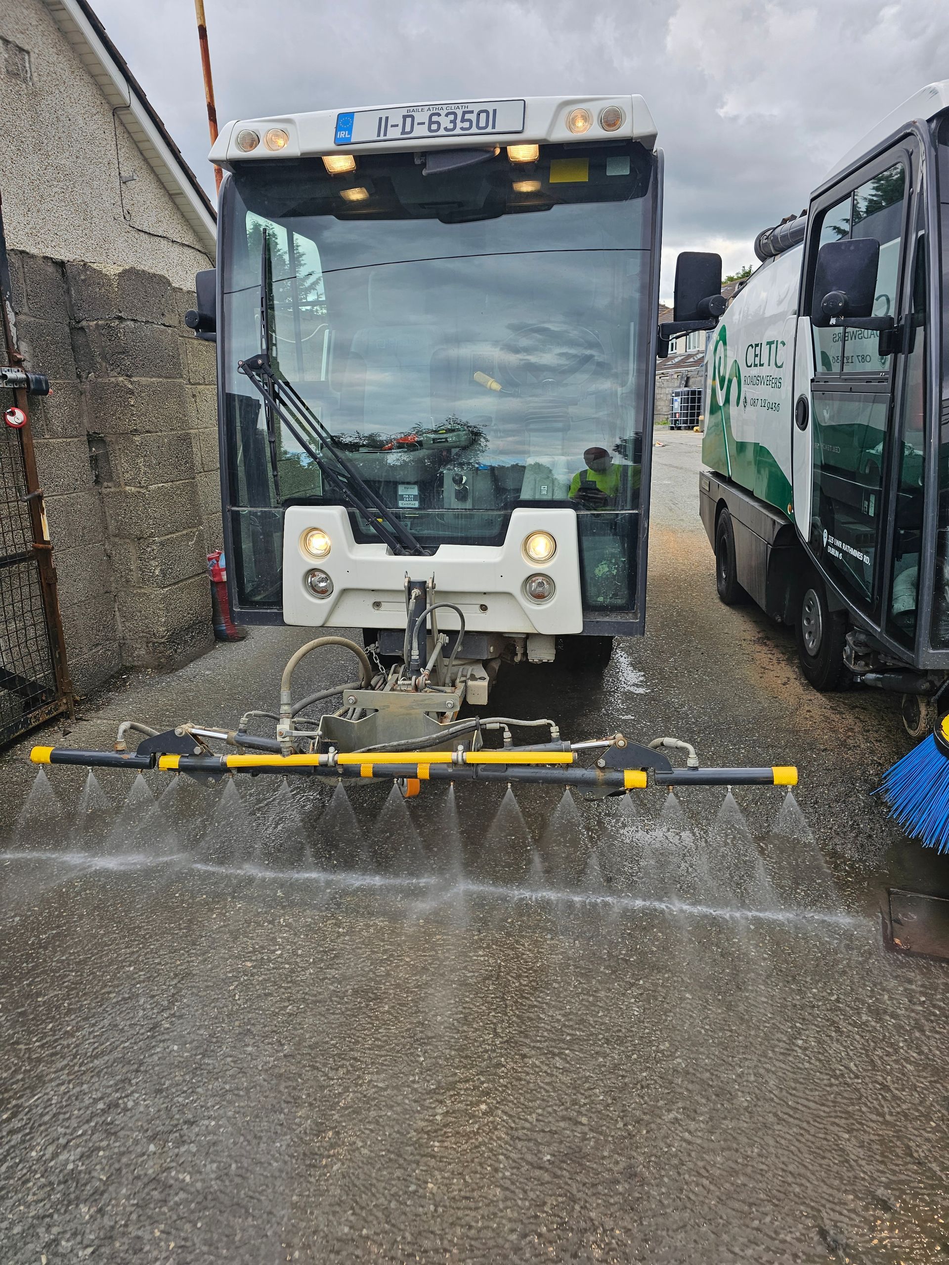 A street sweeper is spraying water on the road.
