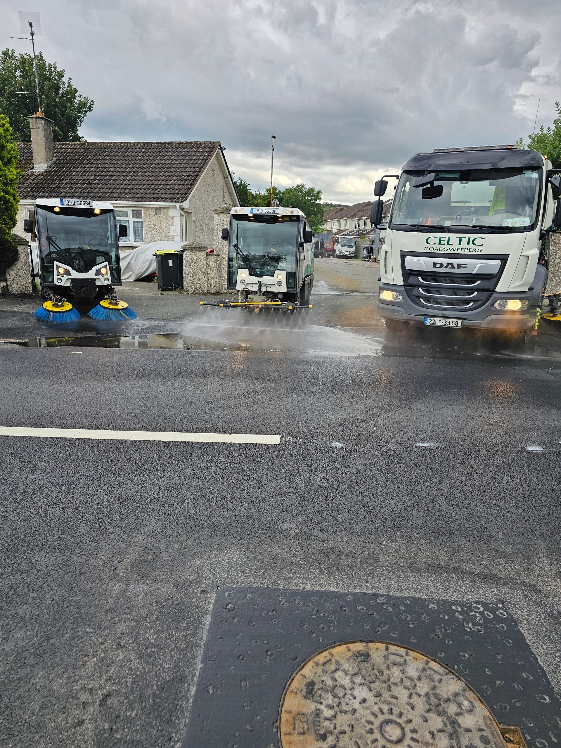 Three trucks are parked on the side of the road in a parking lot.