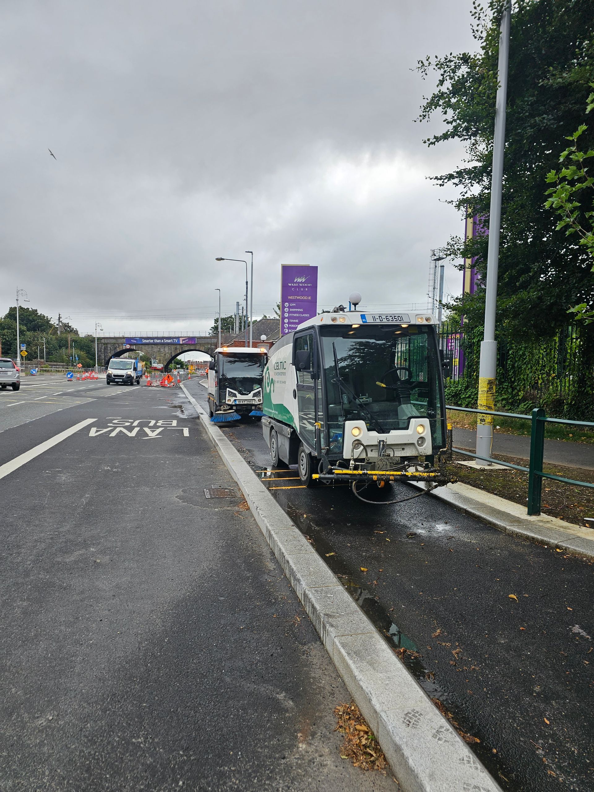 A street sweeper is cleaning the side of a road.