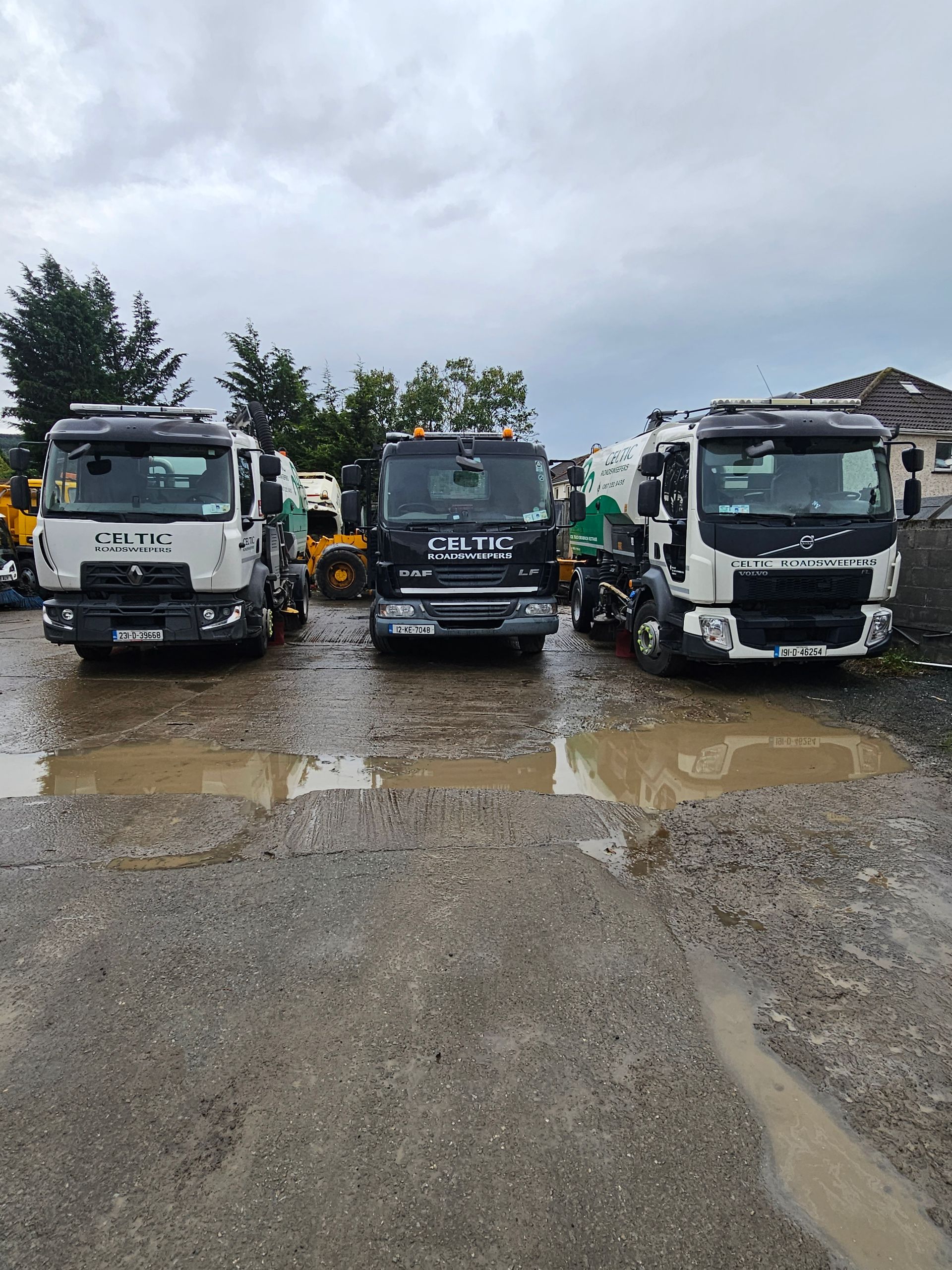 Three trucks are parked next to each other on a muddy road.
