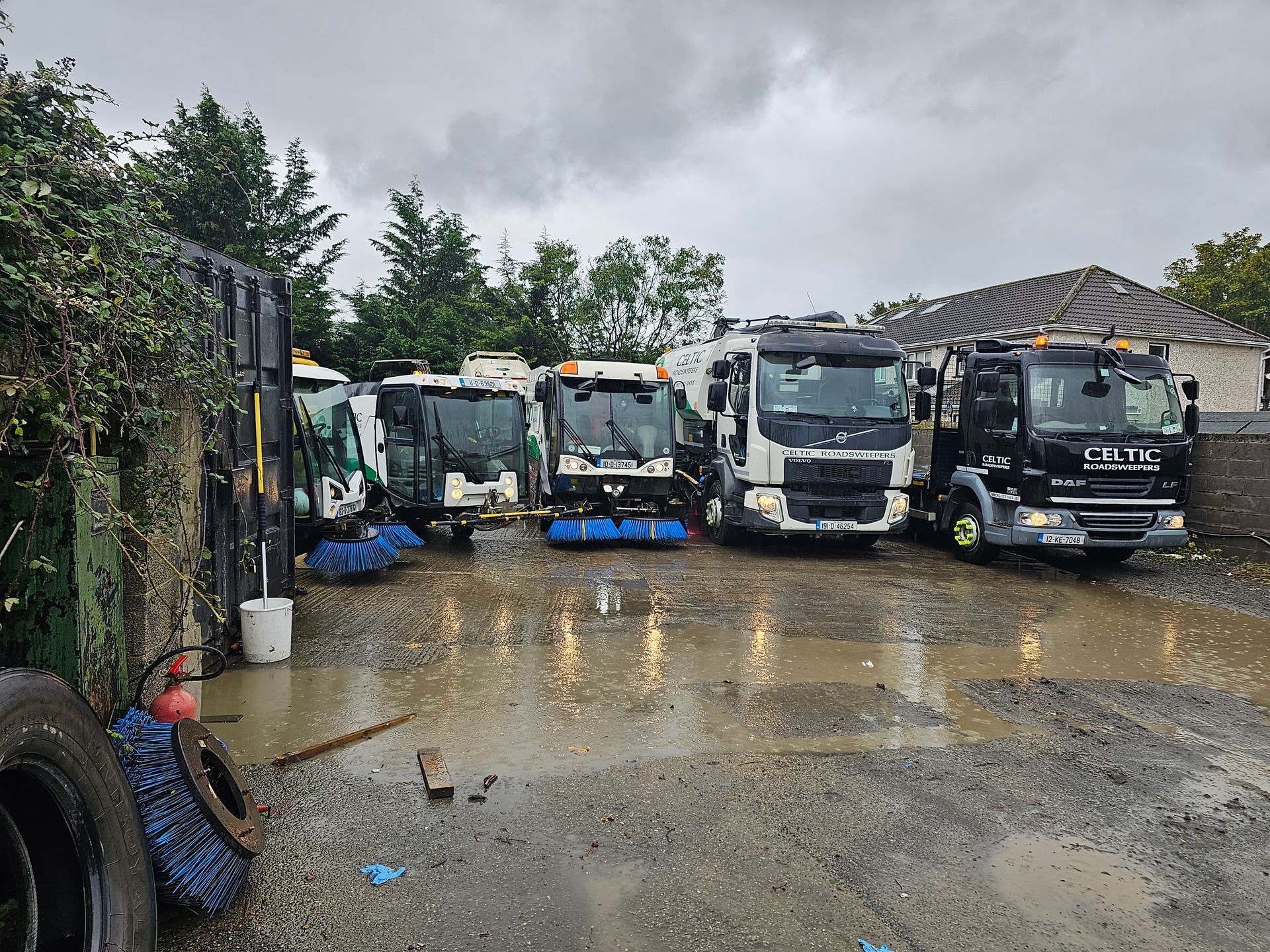 A row of trucks are parked in a muddy lot on a cloudy day.