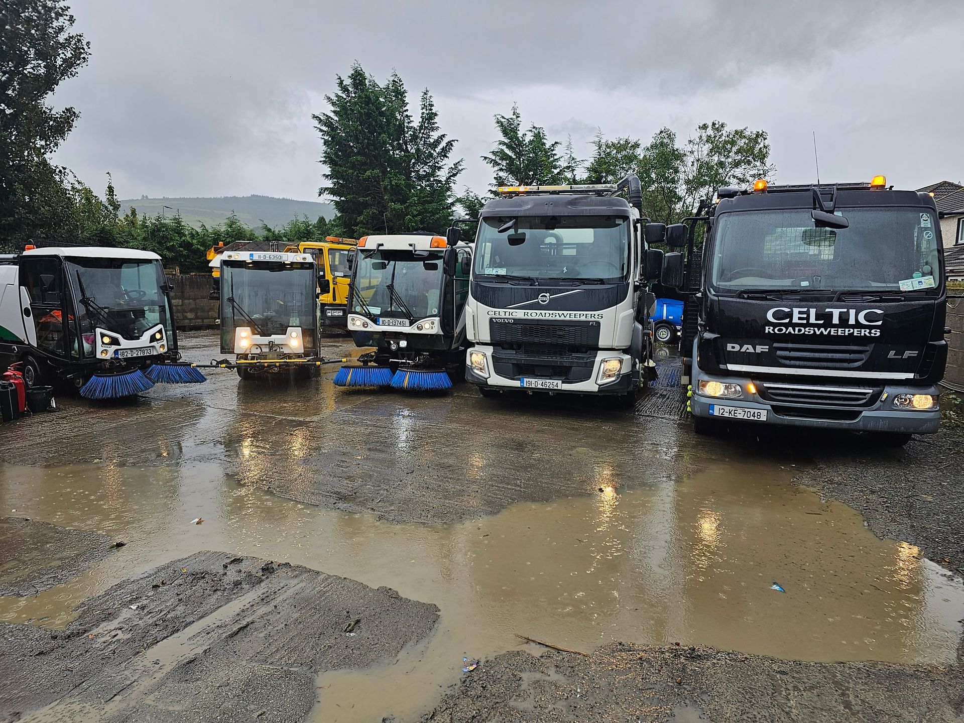 A group of trucks are parked in a muddy parking lot.
