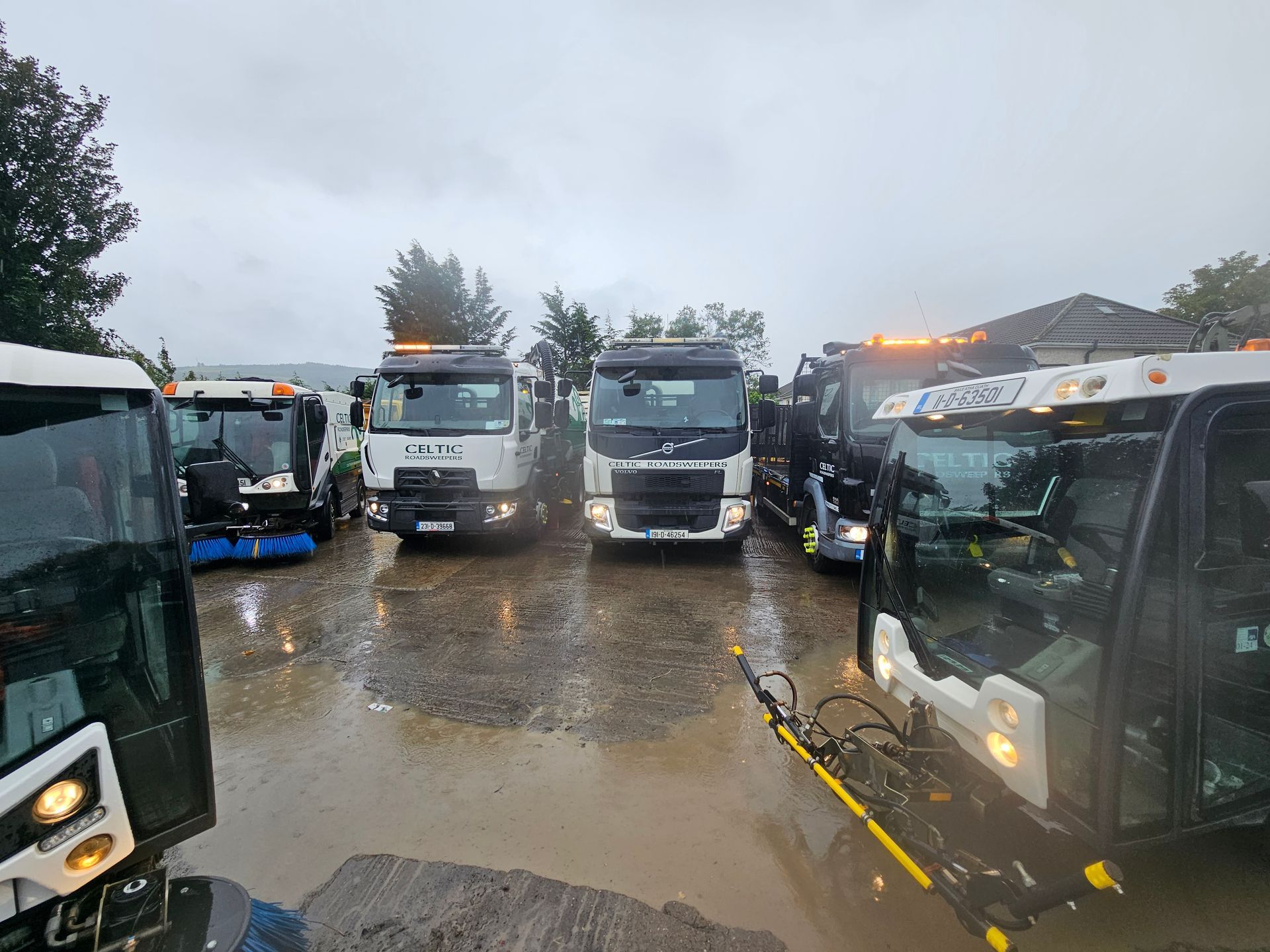 A group of trucks are parked in a parking lot in the rain.