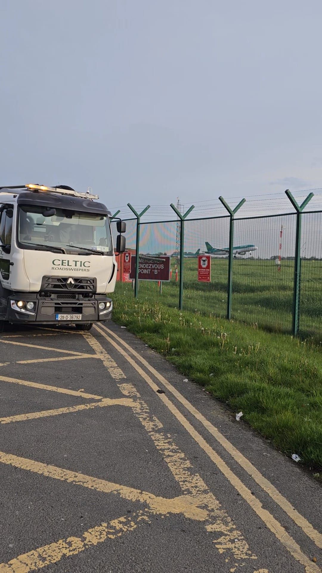 A truck is parked on the side of the road next to a fence.