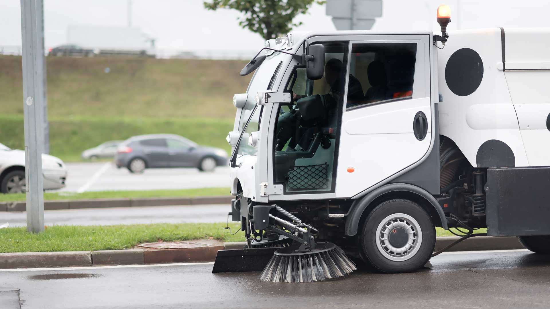 A street sweeper is cleaning the street in the rain.