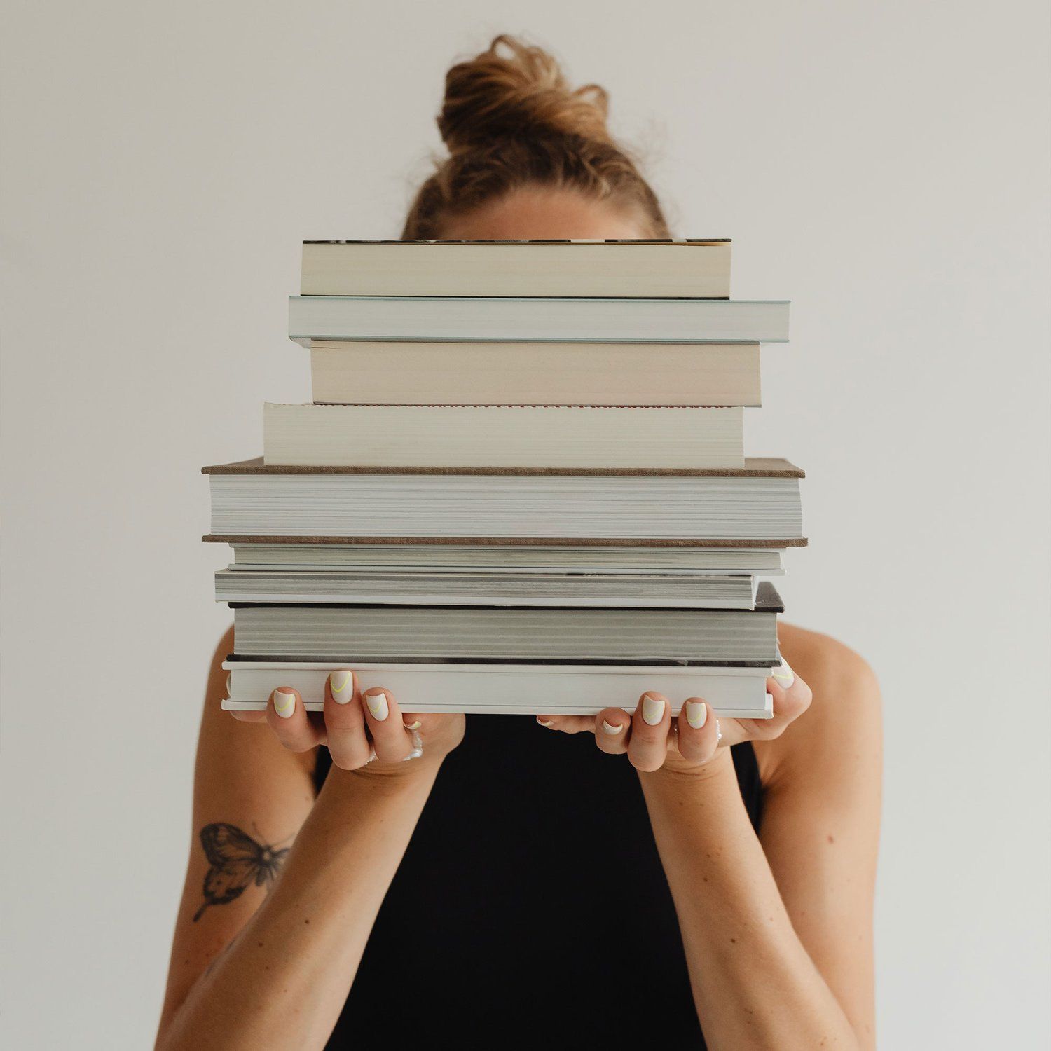 Woman holding a stack of books in front of her face, inviting contact with Cultivating Gratitude in the Dao
