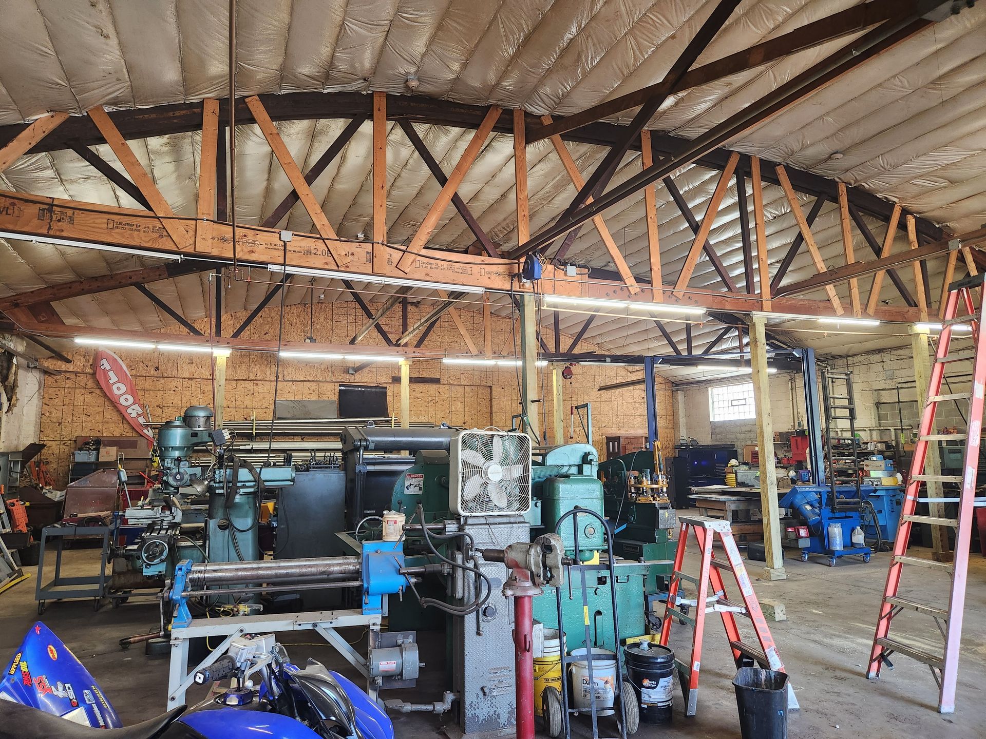 Bowstring truss roof over industrial workshop with machinery in Oshkosh and Milwaukee DMAs
