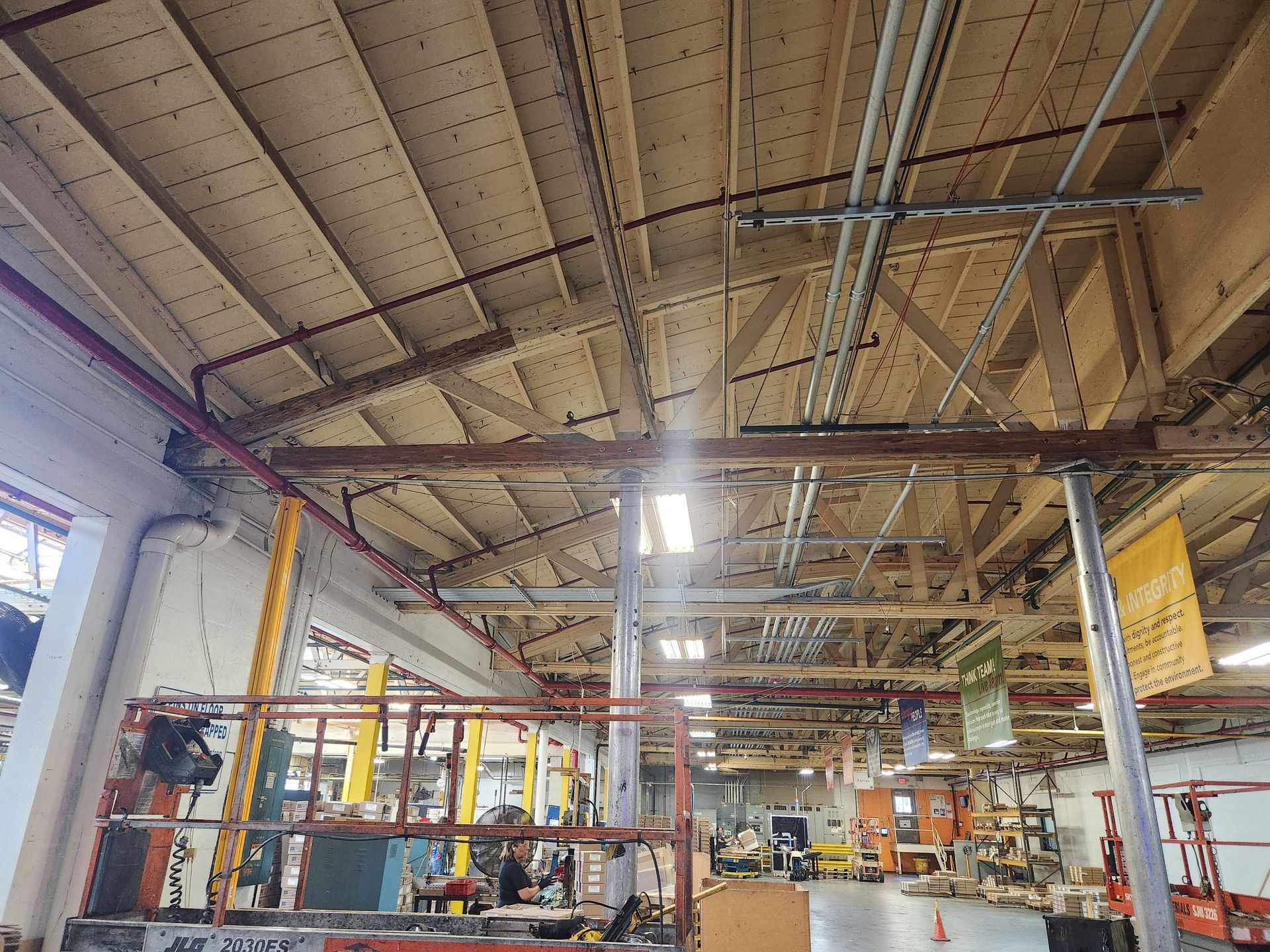 The ceiling of a building with wooden beams and a fan.