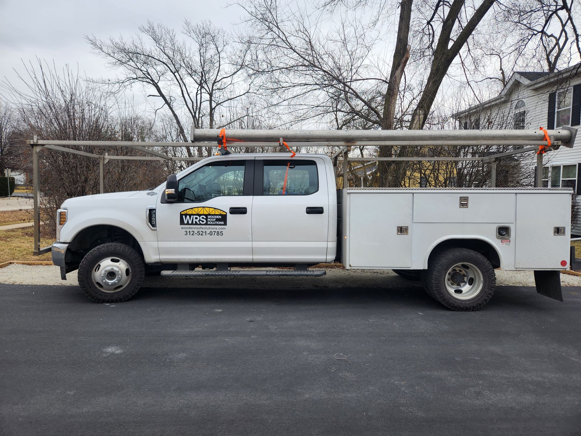 Service truck with WRS logo carrying metal pipes for structural work in Sugar Land, Texas.
