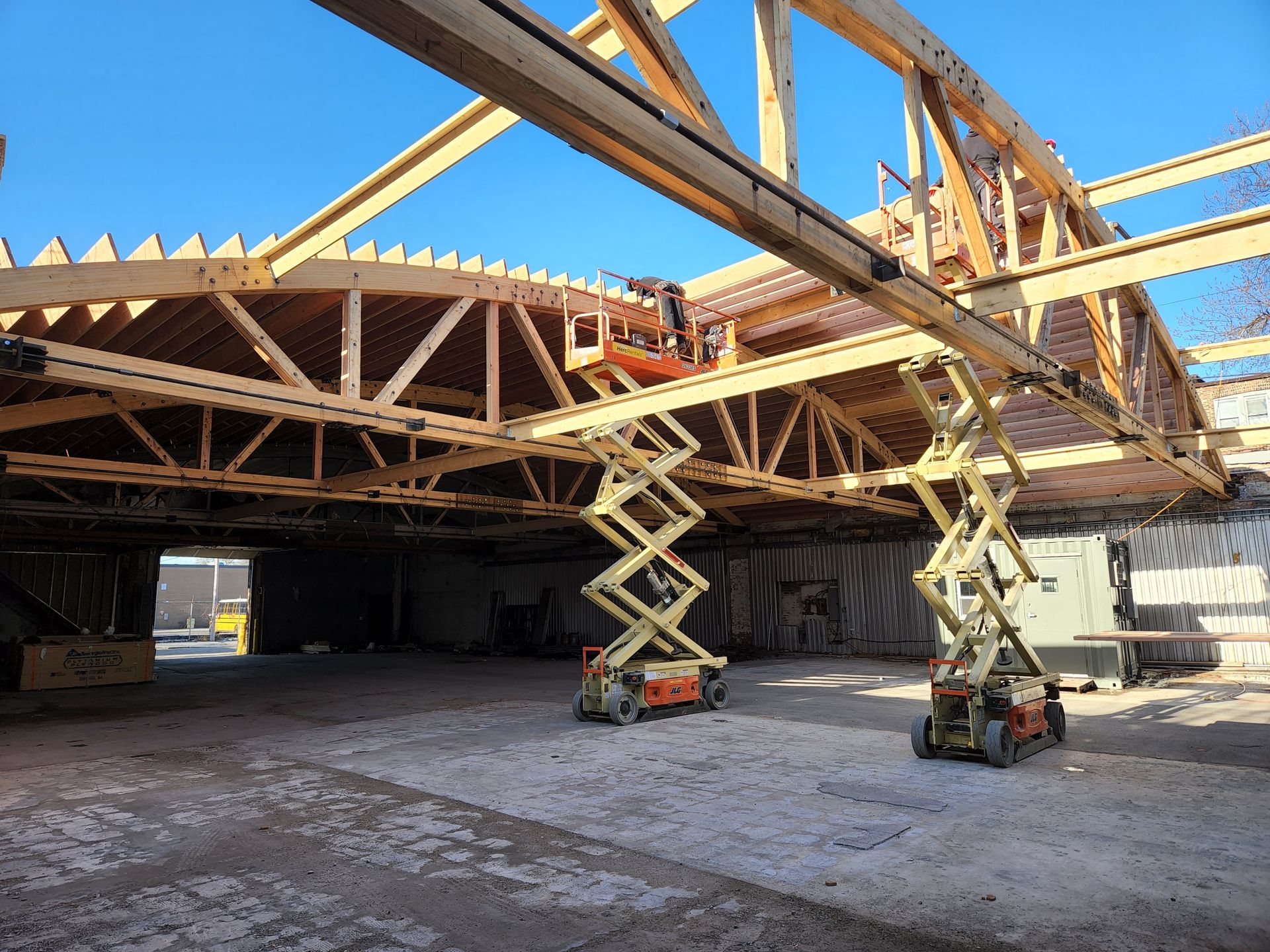 A construction site with a lot of wooden beams and scissor lifts.