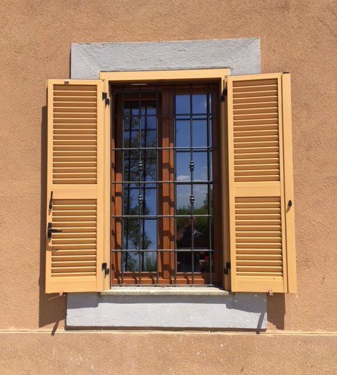 Finestra con grata e persiane bianche