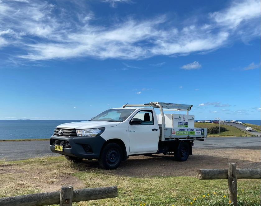 A Man in a Blue Jumpsuit is Working on a Wooden Structure — Country to Coast Pest Control In Valla Beach, NSW