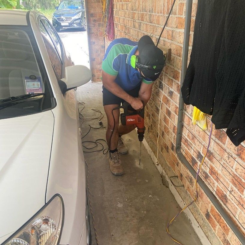 A Man is Using a Drill Next to a White Car — Country to Coast Pest Control In Nambucca, NSW