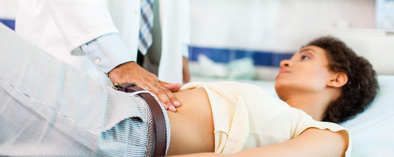 Una mujer está acostada en una cama mientras un médico le examina el estómago.
