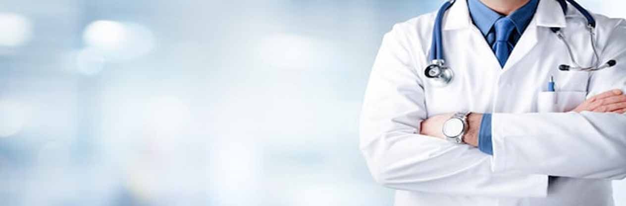 Un médico con un estetoscopio alrededor del cuello está de pie con los brazos cruzados.