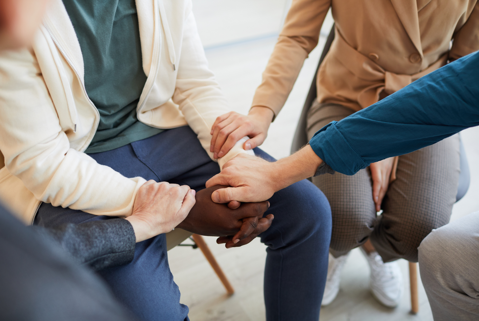 Hands clasped in a circle, people in a support group showing empathy and solidarity.