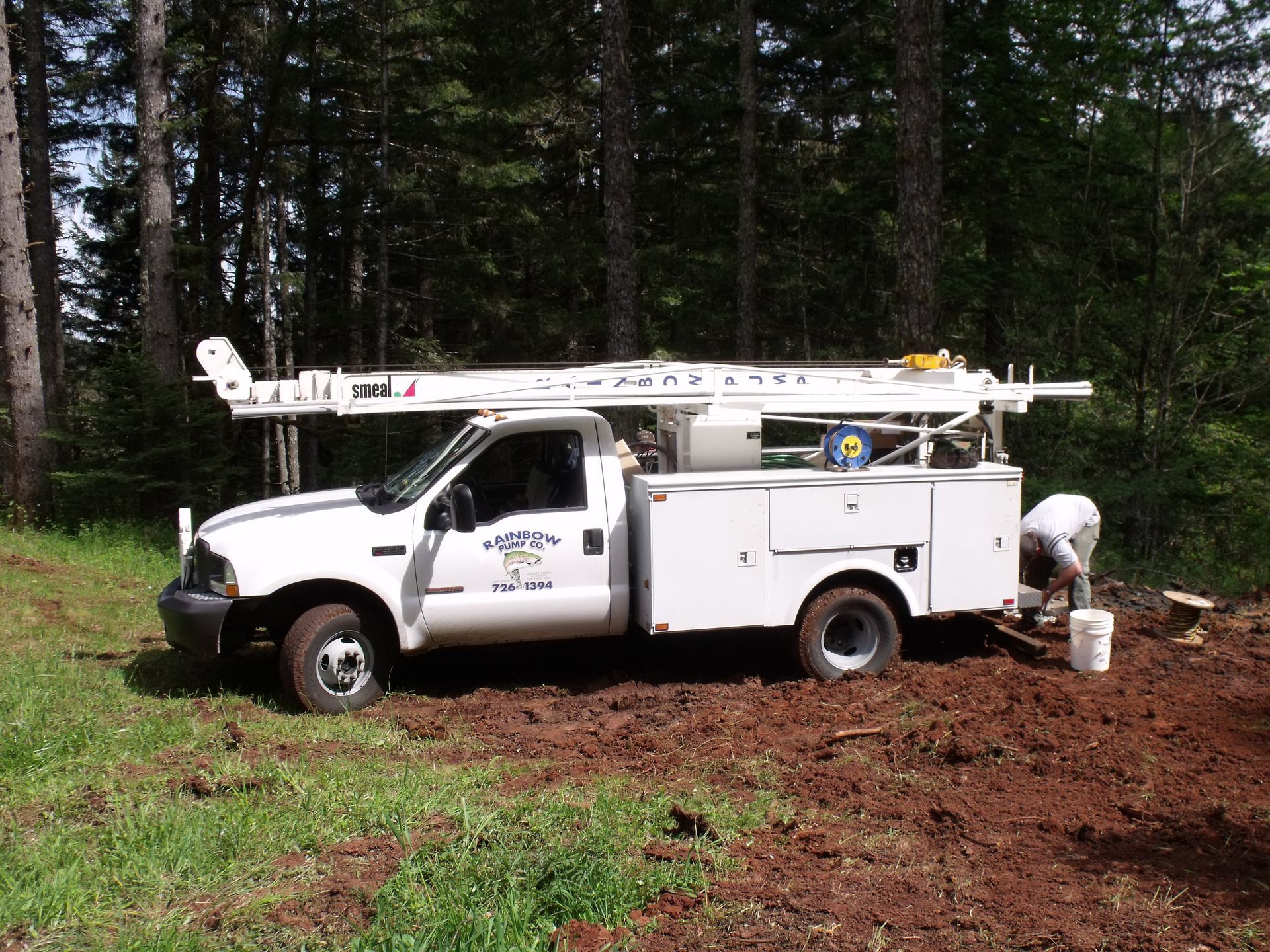 Person in black gloves assembling a water pump with white and orange parts outdoors.