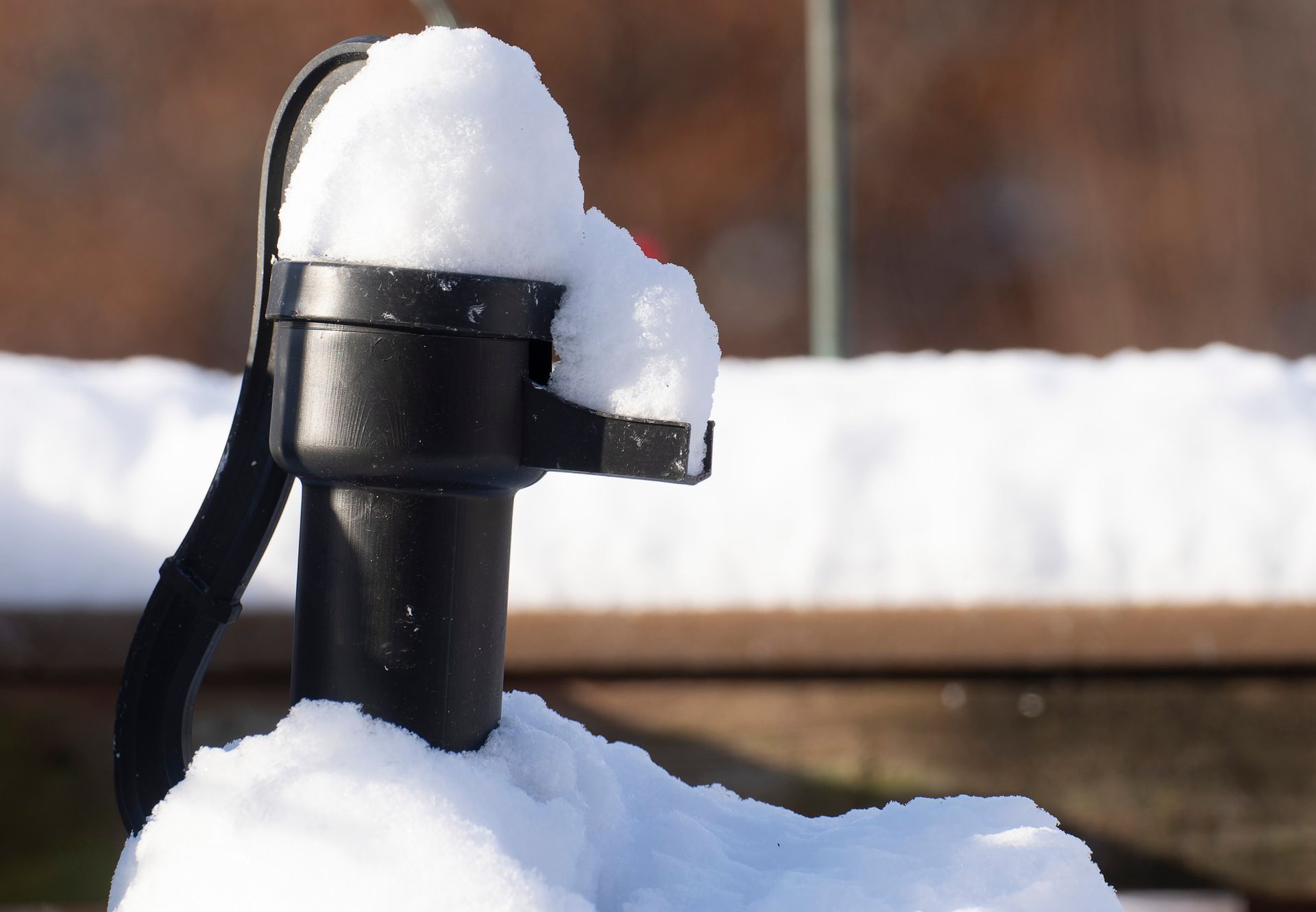Black water pump covered in snow, outdoors.