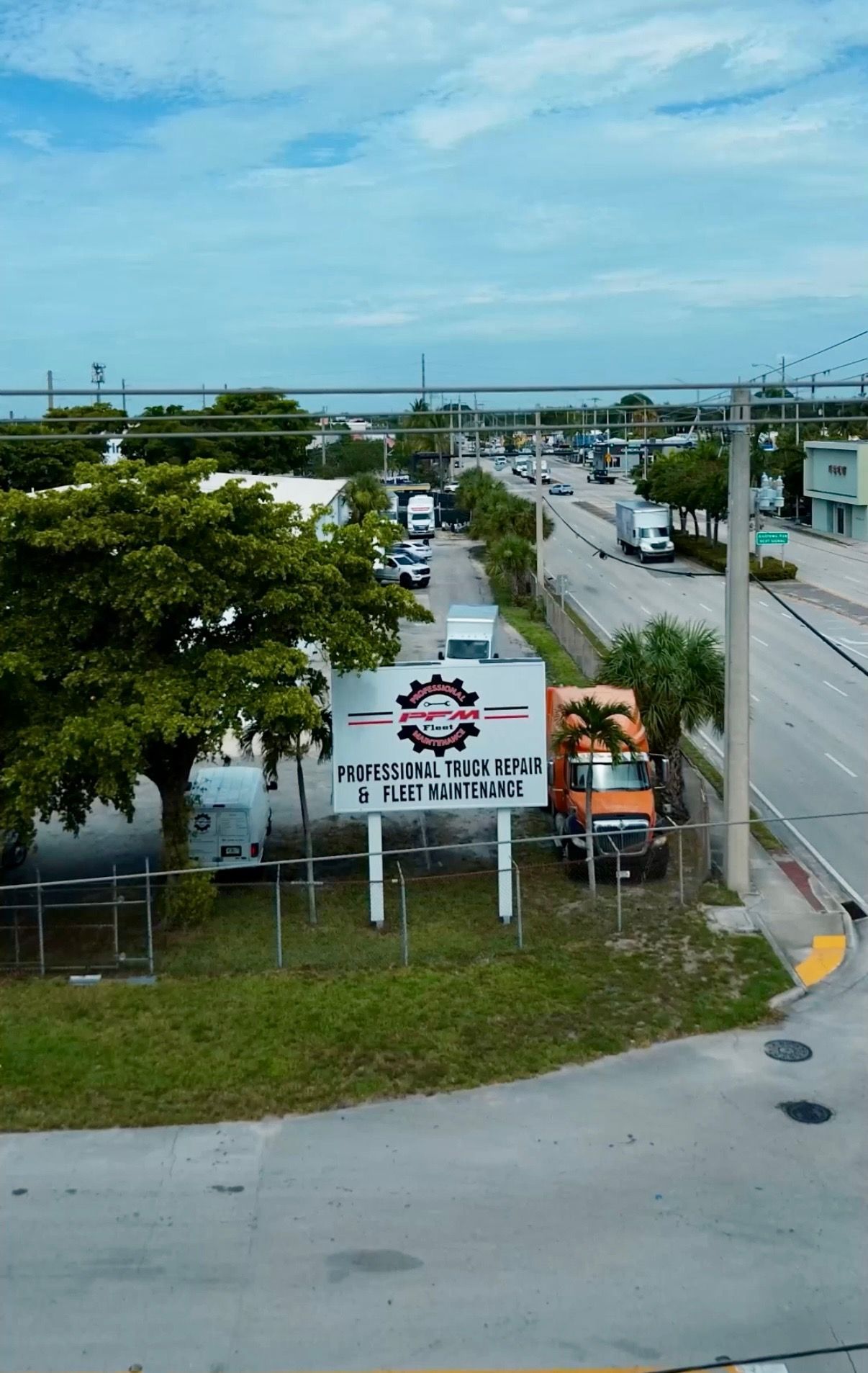 Sign for Kingston Block & Truck Repair near a highway, with an orange truck parked beside it.