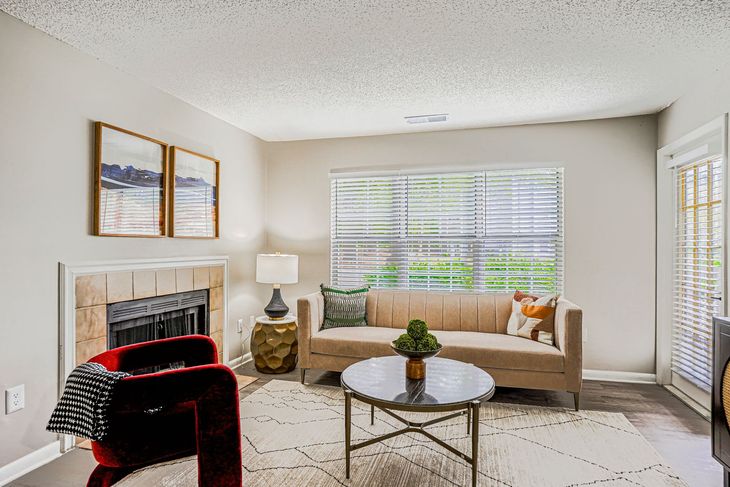 Empty living room with dark wood floors, fireplace, and light gray walls.