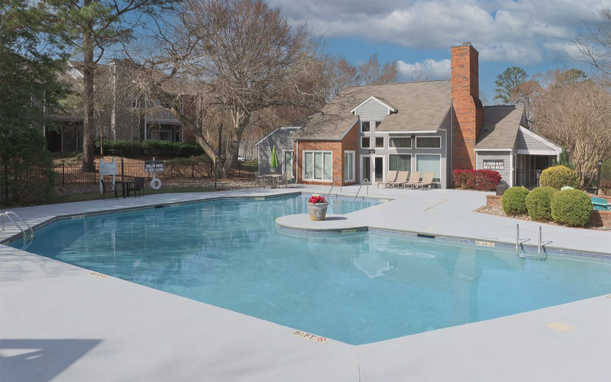 Aerial view of a house with a pool, surrounded by a stone patio and trees.