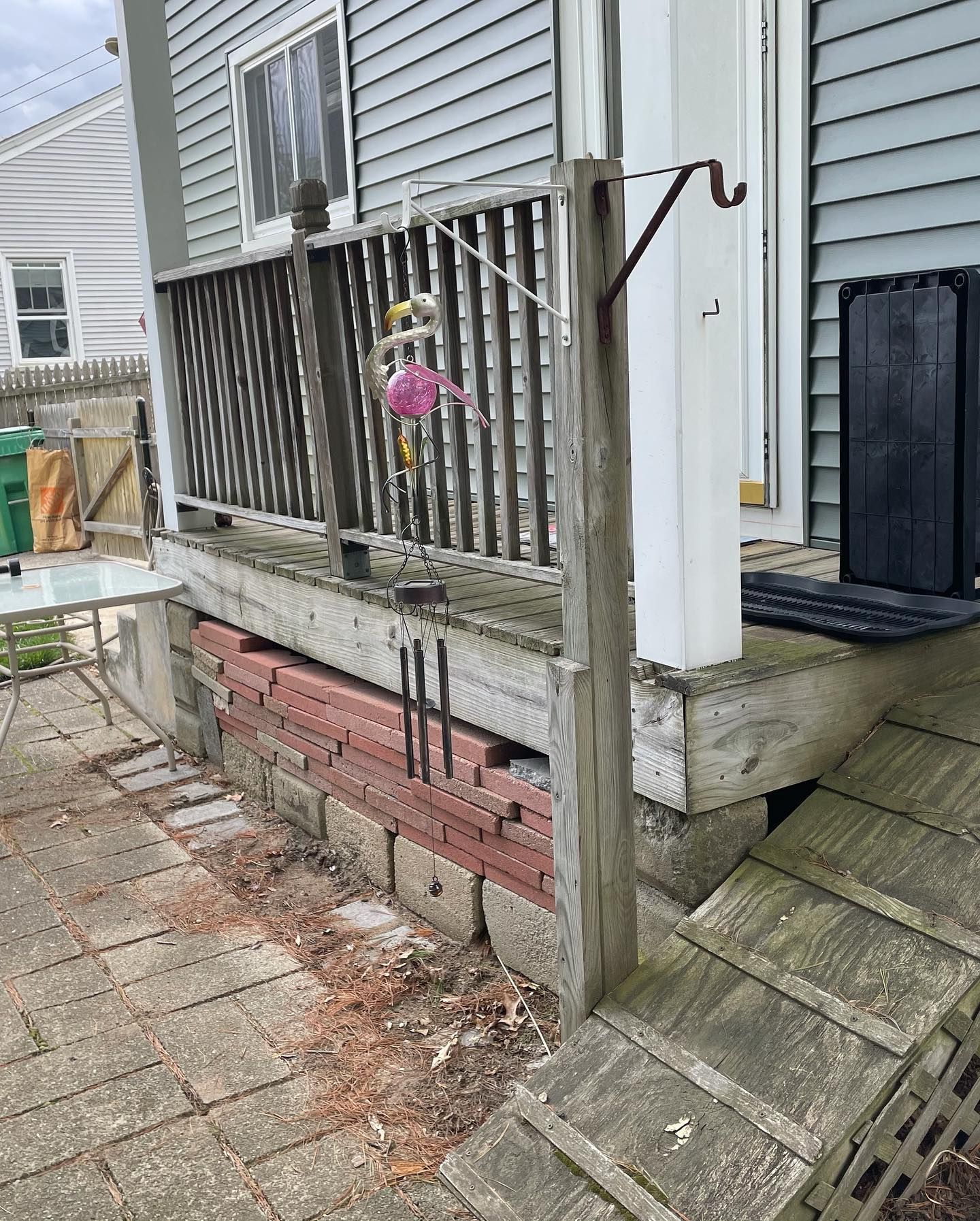 Wooden porch with a ramp. Red bricks support the porch. A pink flamingo hangs from the railing.