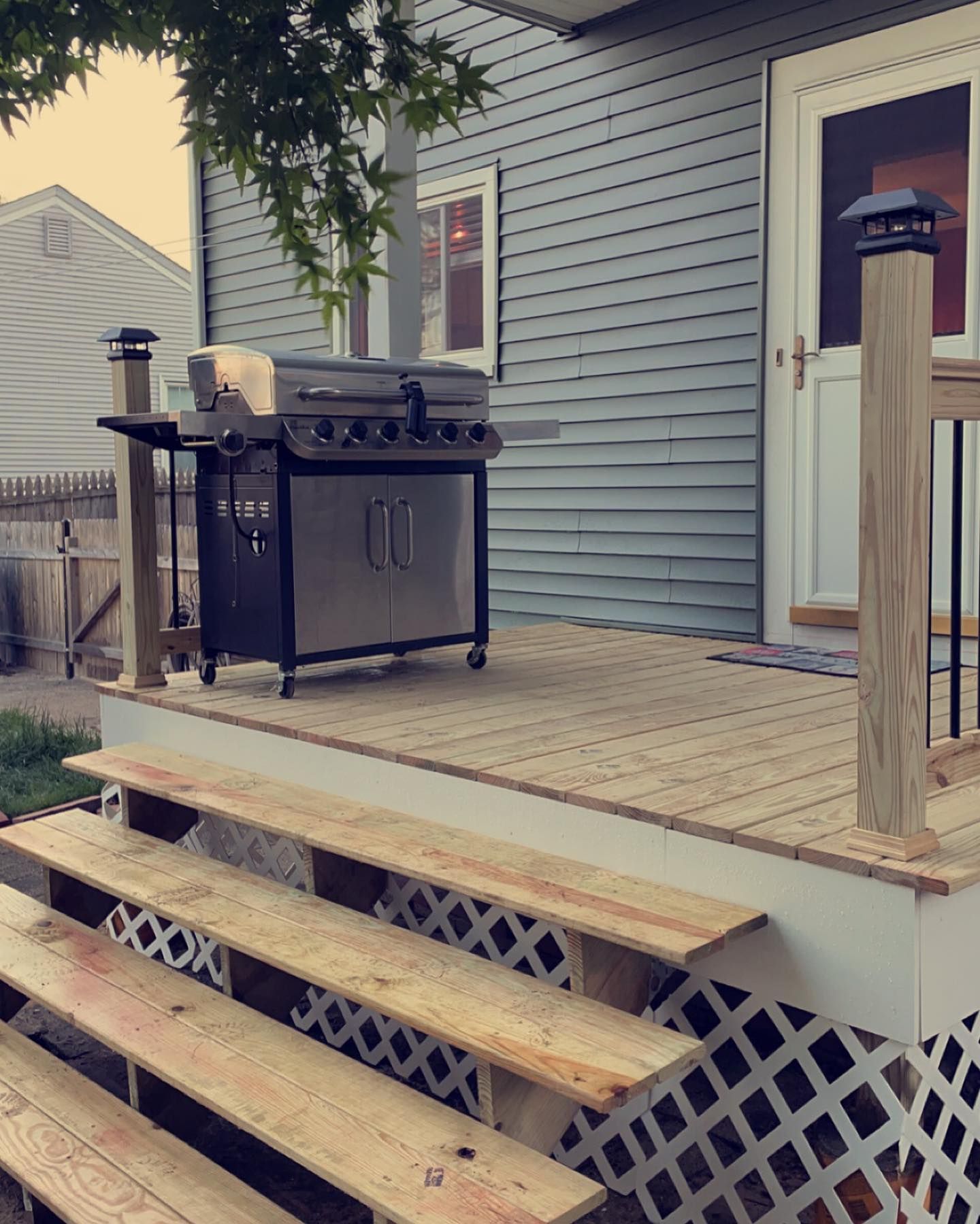 Outdoor deck with a grill and stairs leading down.