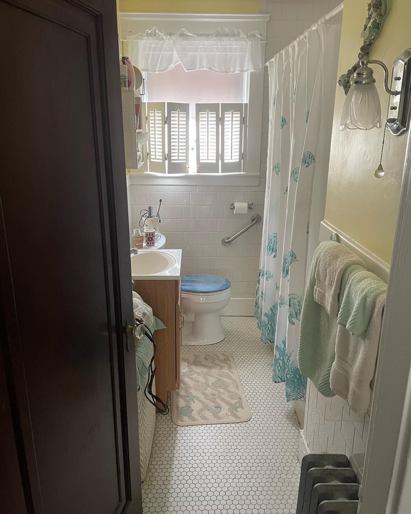 Bathroom with white and teal accents, including a shower curtain and towels. Features a toilet and sink.